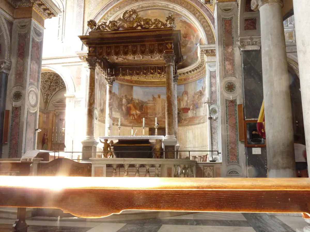 The apse and canopied high altar of San Nicola in Carcere with a fresco in the half dome and marble columns at the sides