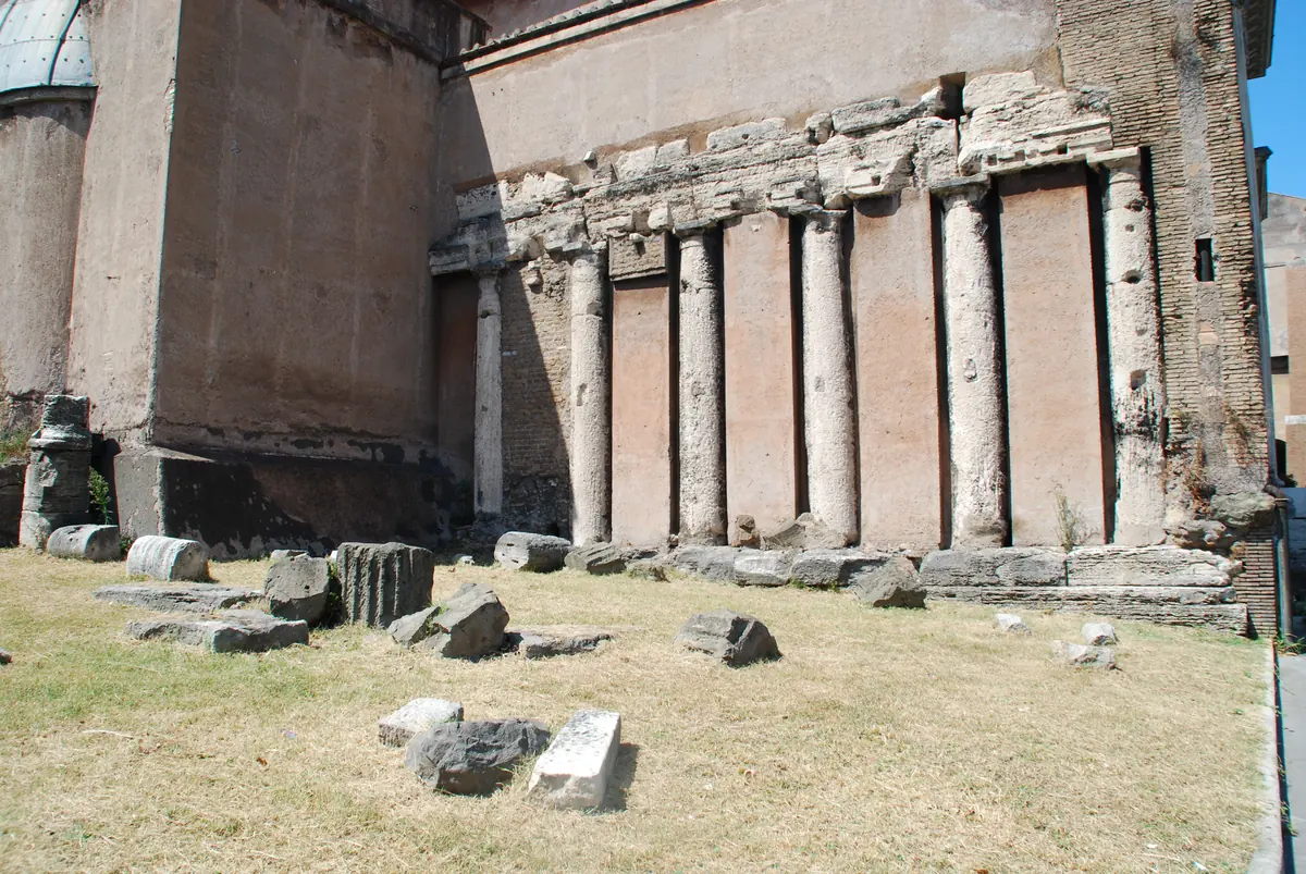 The remains of the southern temple of the Forum Holitorium: a stretch of ancient wall with a row of engaged columns and fallen stone blocks on the ground